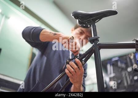 Hispanic man assembling the brake system of a bicycle as part of the maintenance service he performs in his shop. Real people at work. Stock Photo