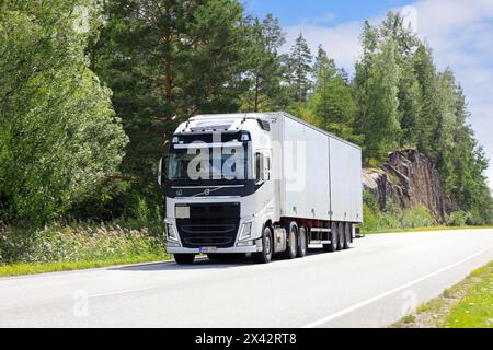 White Volvo FH truck pulls semi trailer along rural highway on a sunny day of summer. Salo, Finland. August 9, 2023. Stock Photo