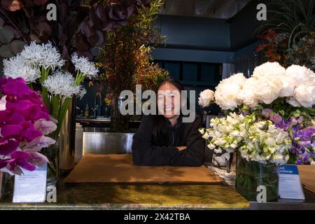 A woman selling flowers at a stall in the South Melbourne market. South Melbourne, Victoria, Australia. Stock Photo