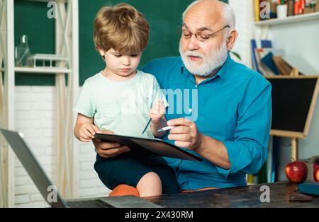 Teacher is skilled leader. Grandfather with grandson learning together. Funny little child having fun on blackboard background. Student and tutoring Stock Photo