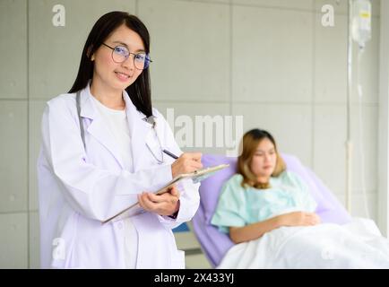 Asian female doctor hand taking note information of patient lying on bed Stock Photo