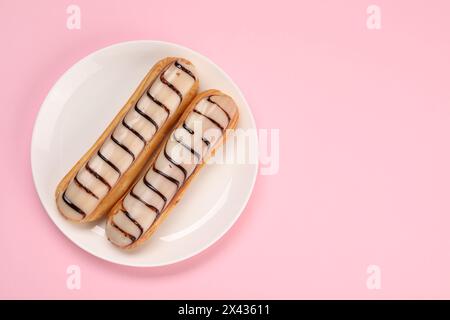 Delicious eclairs covered with glaze on pink background, top view Stock Photo