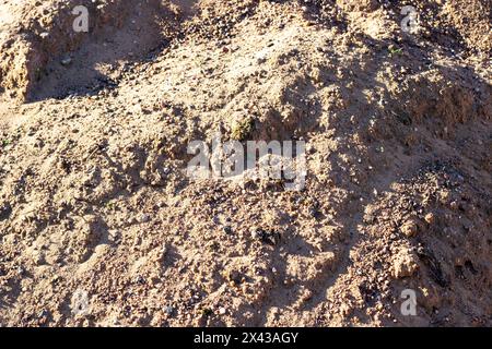 A mixture of soil, brown bedrock, and small rocks resembling a mini landscape. The pattern of rocks creates an interesting contrast in the grassy area Stock Photo