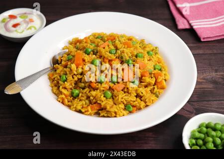 Carrots and Peas Pilaf or Gajar Matar Pulao. It is a one pot rice dish made with Basmati Rice and Vegetables, seasoned with spices, Served with yogurt Stock Photo