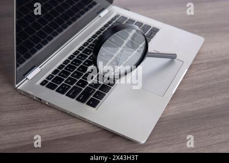 Closeup image of magnifying glass and laptop. Search engine optimization concept. Stock Photo
