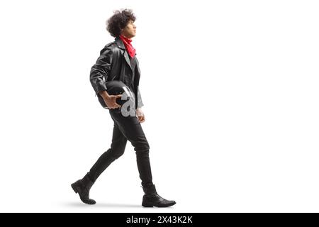 Full length profile shot of a of a young man in leather jacket walking and holding a motorbike helmet isolated on white background Stock Photo