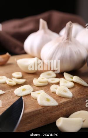 Aromatic cut garlic, cloves and bulbs on dark table, closeup Stock Photo