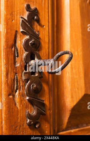 Close-up of antique metal key in keyhole of ornate door lock on wooden armoire in living room inside an old circa 1850 Canadiana style house, Quebec Stock Photo