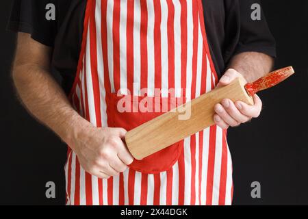 An angry and impatient baker brandishing a wooden rolling pin Stock Photo