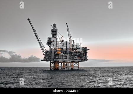 Offshore oil and gas jackup platform in the ocean during sunset. Stock Photo