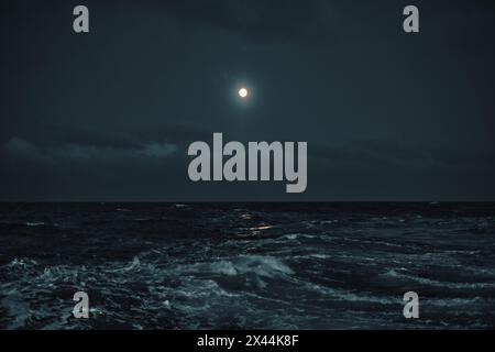 Full moon in the sky over the sea with waves at night. Stock Photo