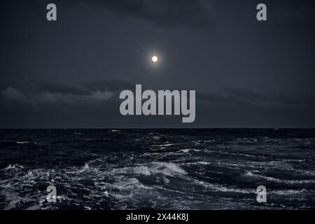 Full moon in the sky over the sea with waves at night. Stock Photo