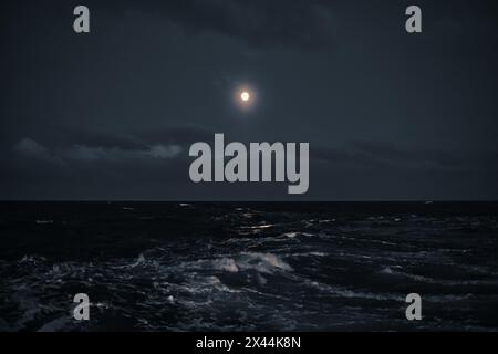 Full moon in the sky over the sea with waves at night. Stock Photo