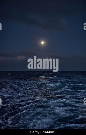 Full moon in the sky over the sea at night during stormy weather Stock Photo