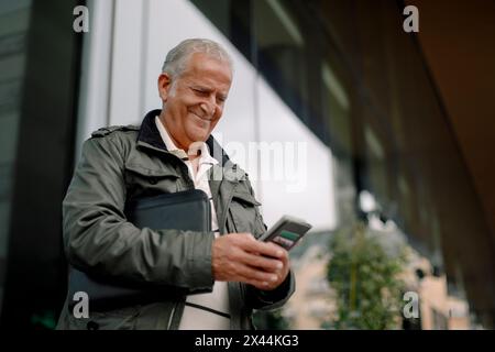 Smiling retired senior man using smart phone Stock Photo