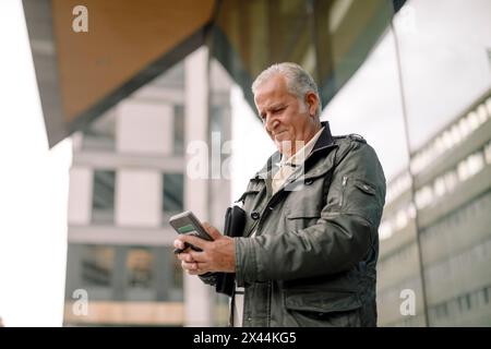 Low angle view of retired senior man using smart phone Stock Photo