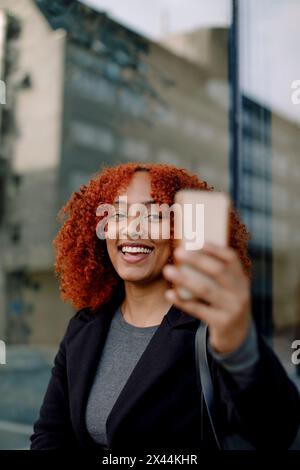 Happy businesswoman using smart phone during video call Stock Photo