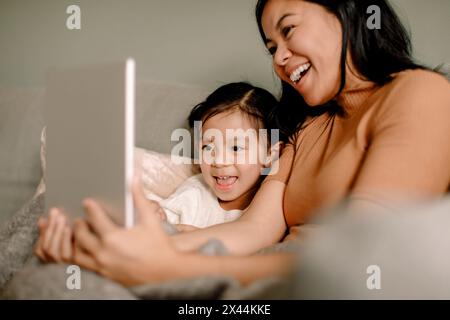 Happy woman with daughter taking selfie through digital tablet at home Stock Photo
