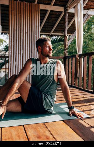 Man doing yoga while sitting on exercise mat at wellness resort Stock Photo
