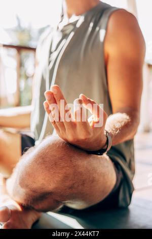 Low section of man practicing Mudra position while doing yoga at wellness resort Stock Photo
