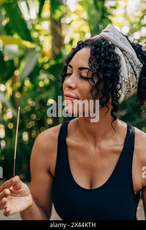 Mature woman smelling incense stick at wellness resort Stock Photo