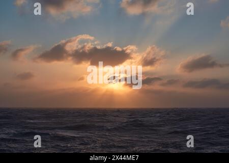 Beautiful sunset in the sea with sun rays shining through the clouds. Stock Photo