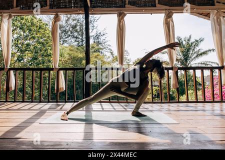 Full length of woman practicing yoga on exercise mat at wellness resort Stock Photo