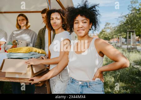 Portrait of confident female volunteers posing with team during charity drive at community center Stock Photo