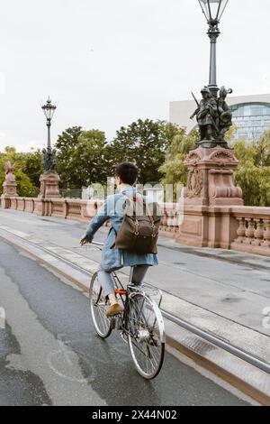 Businessman riding bicycle on lane over bridge in city Stock Photo