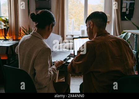 Rear view of male and female freelancers reviewing documents while working from home Stock Photo