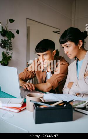 Focused male and female coworkers using laptop while working from home Stock Photo