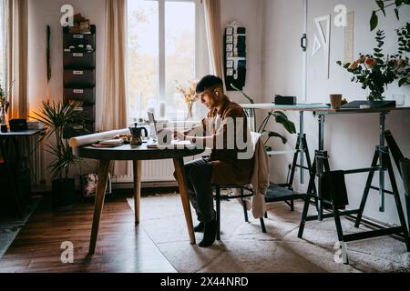 Freelancer working on laptop while sitting on chair at home office Stock Photo