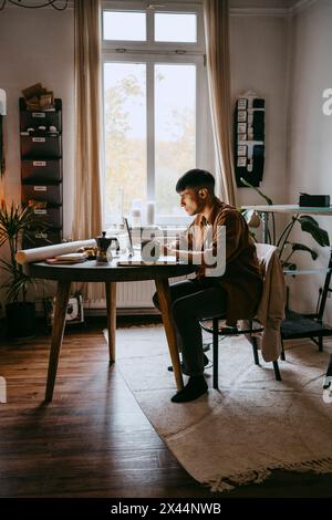 Young male freelancer working on laptop while sitting at home office Stock Photo