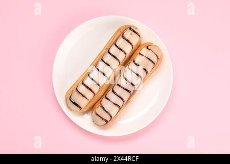 Delicious eclairs covered with glaze on pink background, top view Stock Photo