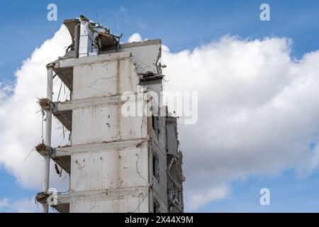 Demolition site, partially demolished high-rise building against blue sky Stock Photo