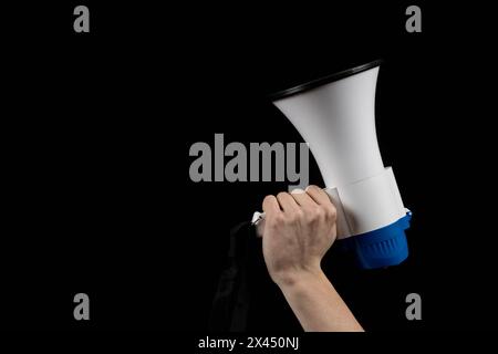 A Megaphone held in a hand isolated against a black background Stock Photo
