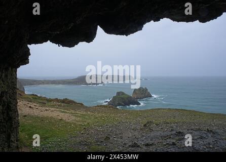 Coastline view from inside a bombed german Second World War bunker on Anse de Pen Hat, Brittany. Lighthouse. Cloudy spring day. Selective focus. Stock Photo