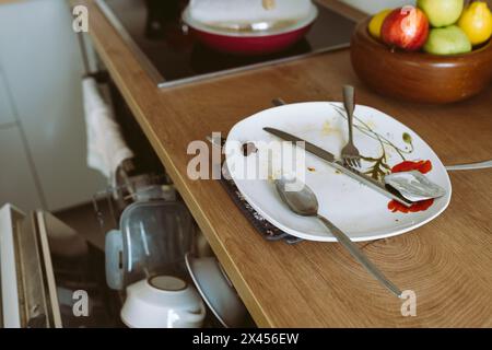 used dirty dishes on wooden kitchen countertop, with built-in dishwasher Stock Photo