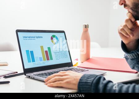 Close-up of a man analyzing company data on a laptop Stock Photo