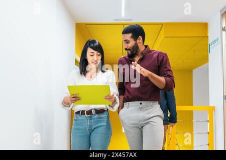 Multiracial coworkers talking reviewing and analyzing company reports in office corridor Stock Photo
