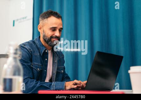 Close-up of a focused man analyzing company data on a laptop in a corking space Stock Photo