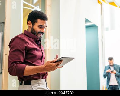 Smiling man in shirt working with a tablet in a coworking Stock Photo