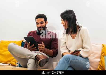Coworkers in an informal meeting during a break. They discuss company data while having coffee in the break area of the modern coworking office Stock Photo
