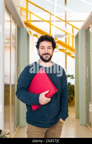 Portrait of a smiling white man in a coworking holding a folder Stock Photo