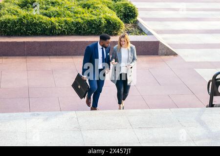 Business colleagues going to the office talking about the company while walking up the stairs Stock Photo