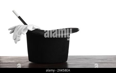 Magician's hat, gloves and wand on wooden table against white background Stock Photo