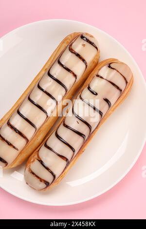 Delicious eclairs covered with glaze on pink background, top view Stock Photo