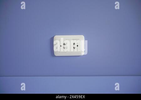 Old electric plug on blue wall. Stock Photo