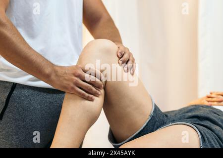 Close-up of a physiotherapist massaging the leg of an unrecognizable patient. The patient is receiving recovery treatment in a physiotherapy clinic Stock Photo