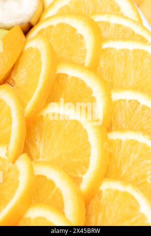 A mix of citrus fruits including sliced oranges, clementines, and Rangpur surrounded by a banana in the background. A colorful display of natural food Stock Photo